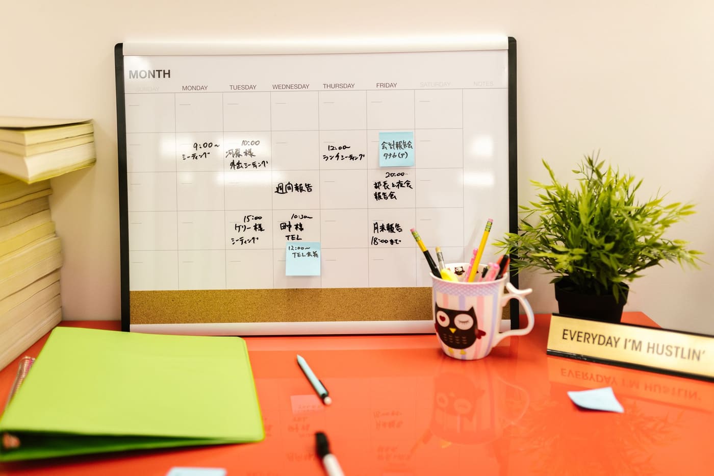 A neat desk with a calendar, a small plant, and stationery